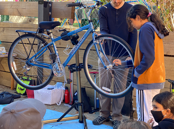 student and teacher looking at a bicycle on the stand 